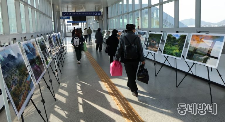 영천역 승강장 입출구 통로에 전시된 제17회 영천관광 전국사진공모전 입상작품을 철도 이용객들이 관람하고 있다.